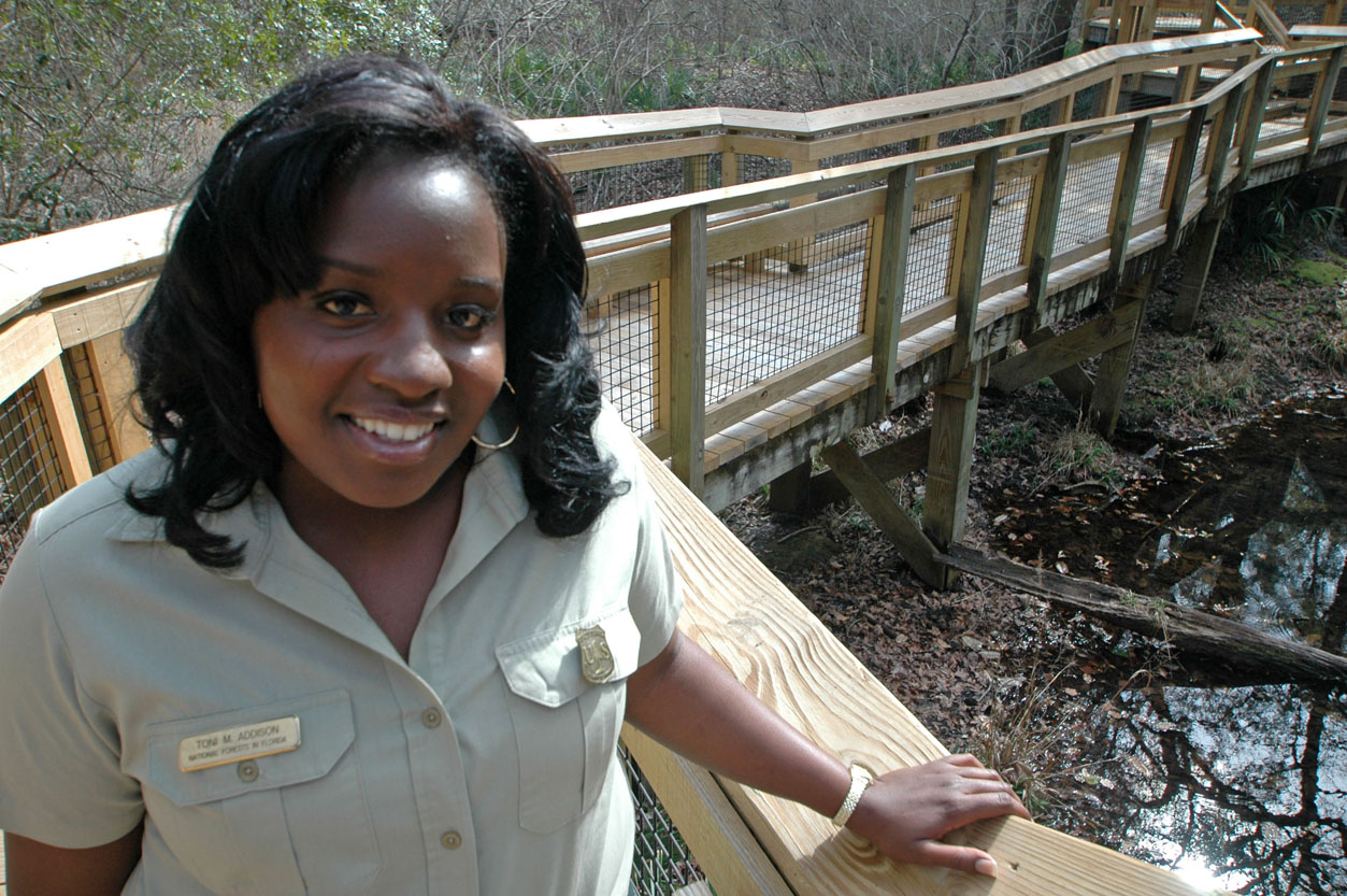 Uniformed employee standing on a trail bridge.