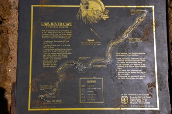 A metal plaque displays interpretive information about Lava River Cave in gold writing
