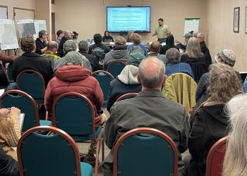 An audience listens to a Forest Service employee give a presentation.