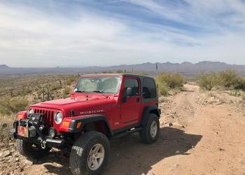 A red jeep on a dirt road