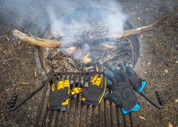 Bike gloves drying over a smoky campfire
