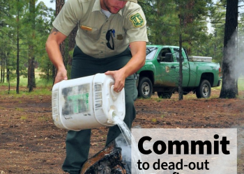 A photo of a forest service employee dumping water on a campfire in the forest. Text states, Commit to dead-out campfires, always. USDA and Forest Service logo.