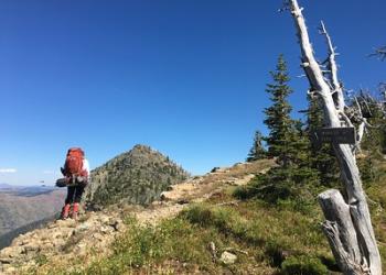 A hiker takes a break on the trail near the summit