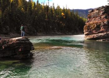 Two individuals fly fishing along the river's edge