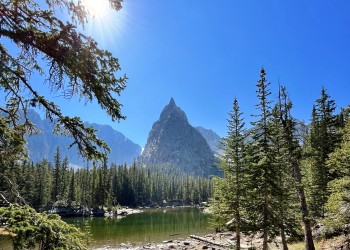 high mountain lake with trees surrounding and a large mountain jutting in background