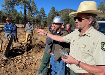 A Forest Service employee in uniform leads a tour with partners