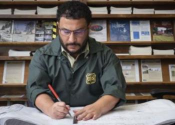 engineer in a Forest Service uniform is at a table working