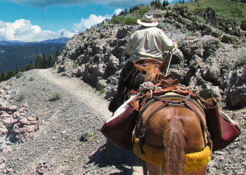 A horse packer rides along a scree trail in the Pecos Wilderness