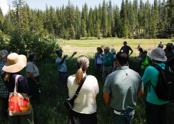 a man speaks to a group of people in an open field
