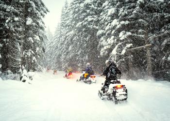 A group of people ride OSVs on a snowy day.