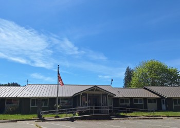 the Cowlitz Valley Ranger district Office with American Flag on a pole in front of the office building, and blue sky above.