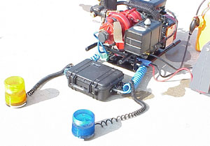 The complete system, consisting of the pump, battery pack, receiver and 2 flashing strobe beacons.  The strobes are connected with extendable, coiled cord allowing them to be placed where they are most conspicuous.