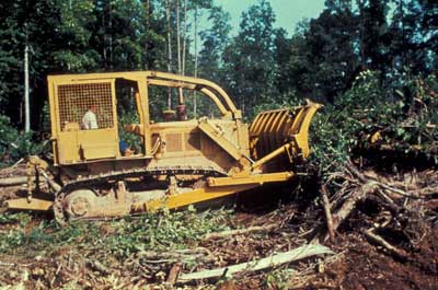 Photo of a bulldozer moving a pile of slash and debris.