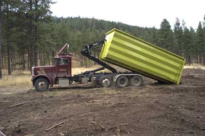 Photo of a semi-truck with a roll-on/roll-off bin on it. 