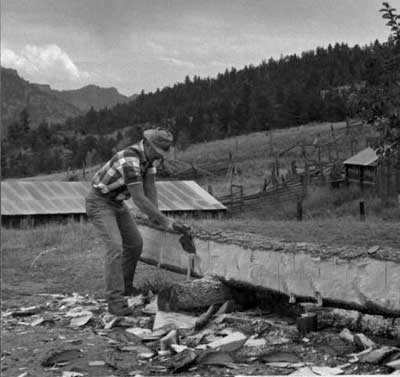 Photo of a man hewing with a broad ax.