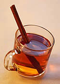 Glass of hot cider with a cinnamon stick in it.