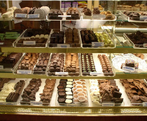 A candy shop display case stocked with various kinds of chocolate candies. 